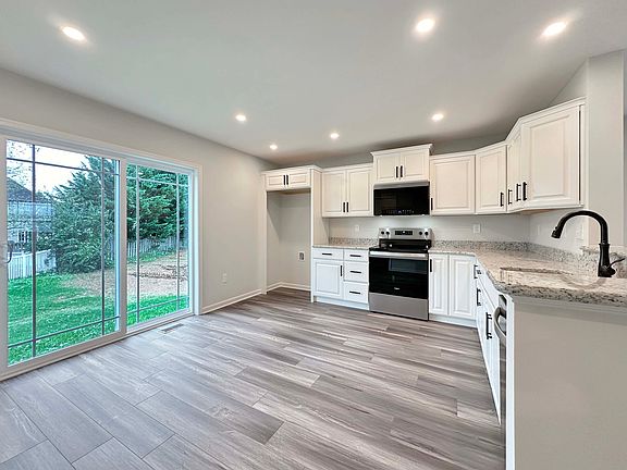Bright kitchen with white cabinetry, granite countertops, and stainless-steel appliances. Sliding gl