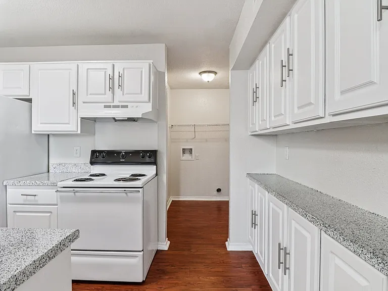 Bright, modern kitchen with sleek white cabinetry and speckled countertops, complete with elegant wood-style flooring. Bright, modern kitchen with sleek white cabinetry and speckled countertops, complete with elegant wood-style flooring.