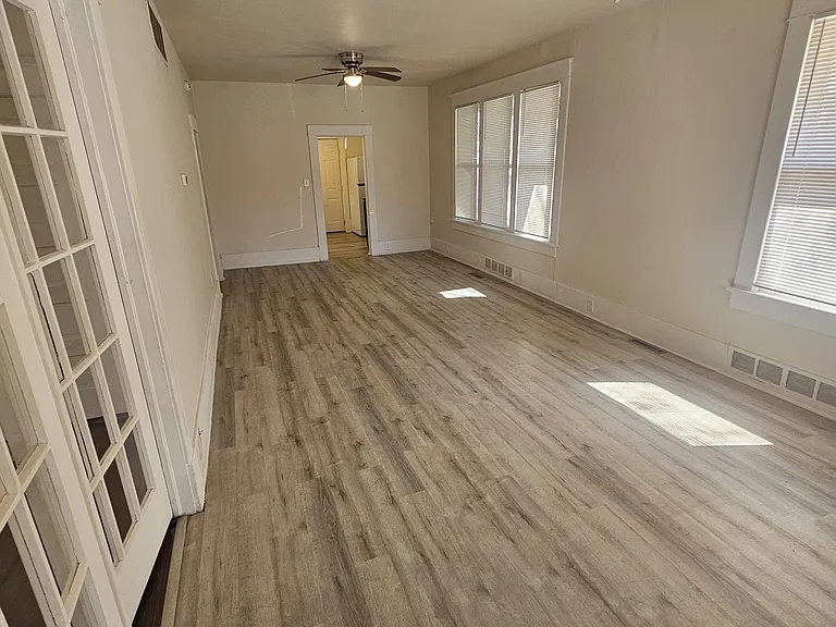 Walking in the front door. Big living room with high ceilings and natural light. Kitchen in back. Bedroom or dining room with French doors to the left.