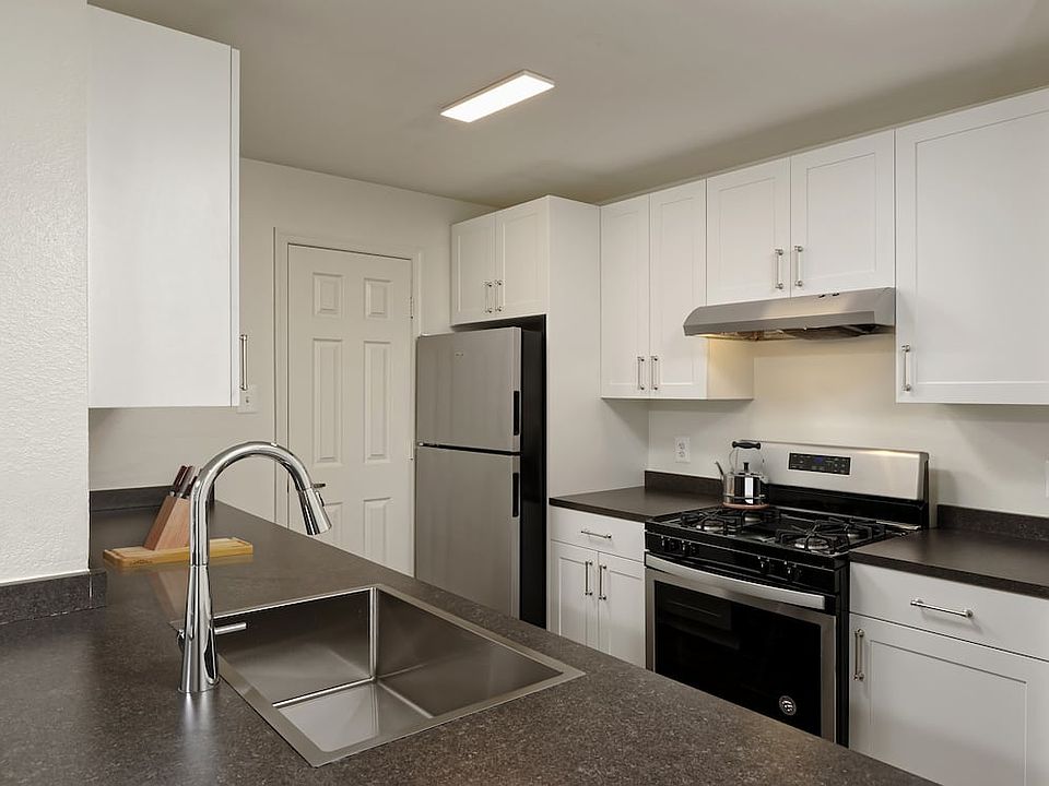 Renovated Package II kitchen with white cabinetry, dark grey laminate countertops, stainless steel appliances, and hard surface flooring