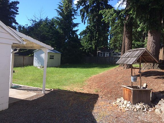 Back yard fully fenced. Parking space continues beyond the fence/gate. Storage shed and side enterance just out of sight on the left. Storage shed with power and light in the distance.