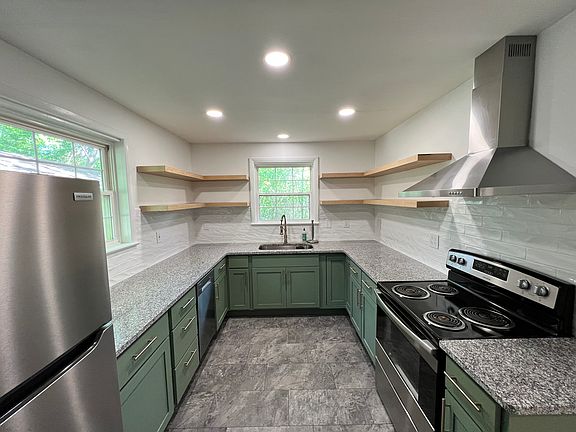 We love our farmhouse kitchen. All appliances are only two years old and the kitchen has a small pantry, open shelving, dishwasher, refrigerator, and oven with white tile backsplash.