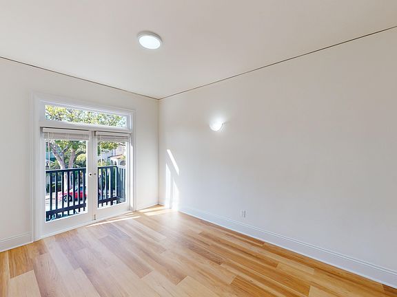 Sunlit room with a large window and wood-like flooring