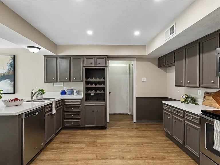 Kitchen featuring wood-finish flooring, white quartz countertops, lots of cabinetry with brushed nickel hardware, and stainless steel appliances