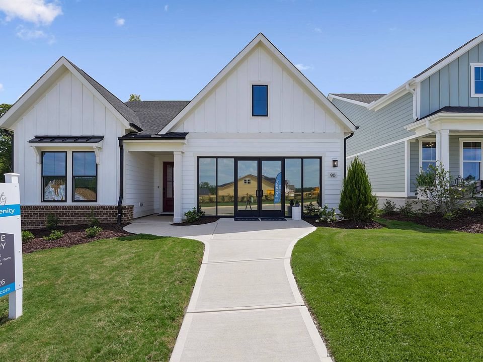 A modern, two-story residential home with a gabled roof, white siding, and a brick exterior, surroun