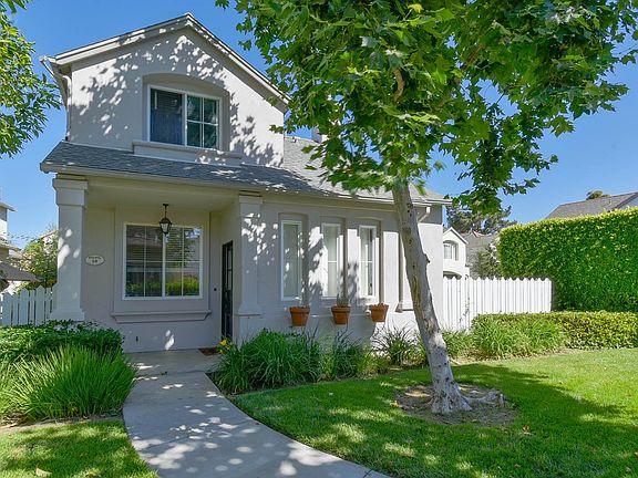 The front of the house with the kitchen window looking out next to the front door. Fence on the right side encloses its patio space.