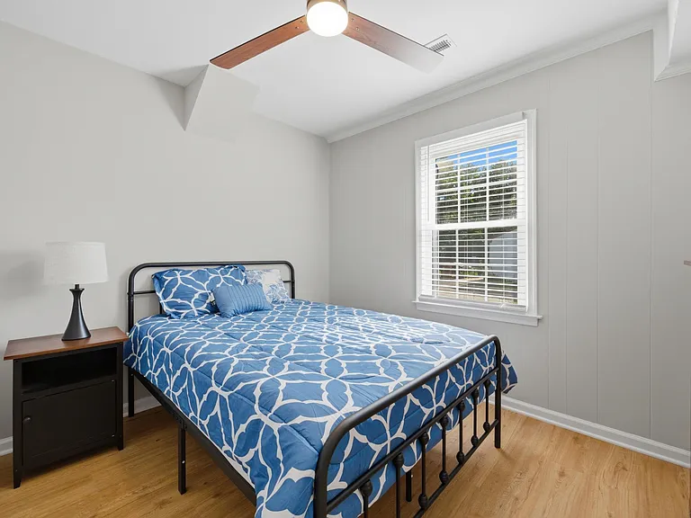 Well-kept bedroom with a ceiling fan, hardwood-style floors, and a large window with blinds for comfortable everyday living.