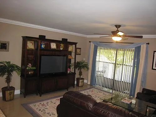 view from front door of living room TV in wall unit and slider to large screened patio