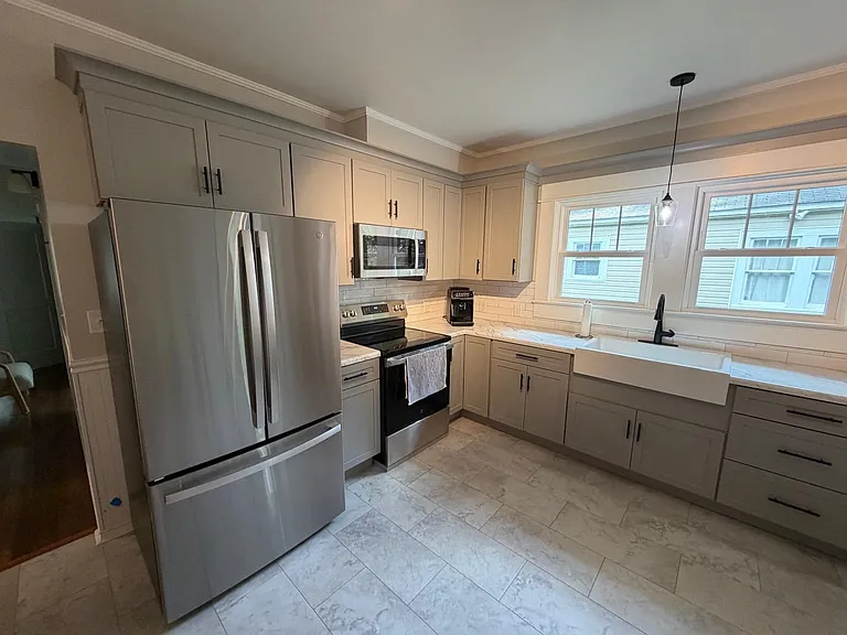 Updated kitchen with stainless appliances, ample cabinet storage, and a farmhouse sink set beneath a wide window.