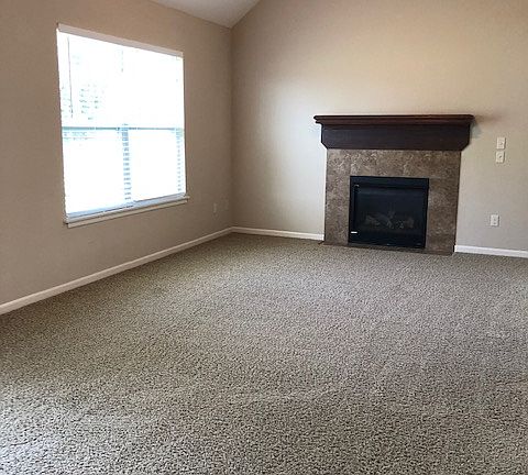 Gas fireplace in living room with vaulted ceiling.