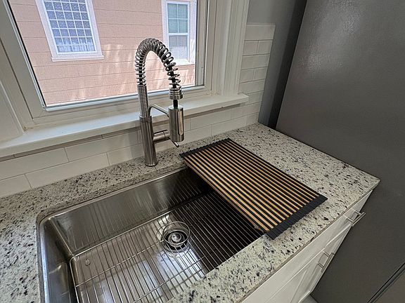 Luxury stainless steel sink with pull-down faucet, custom cutting board, and magnetic drain rack.
