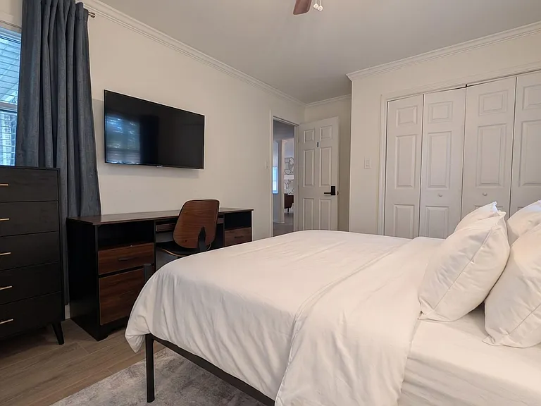 Well-appointed bedroom with a comfortable bed, ceiling fan, TV, work desk, and a spacious double-door closet.