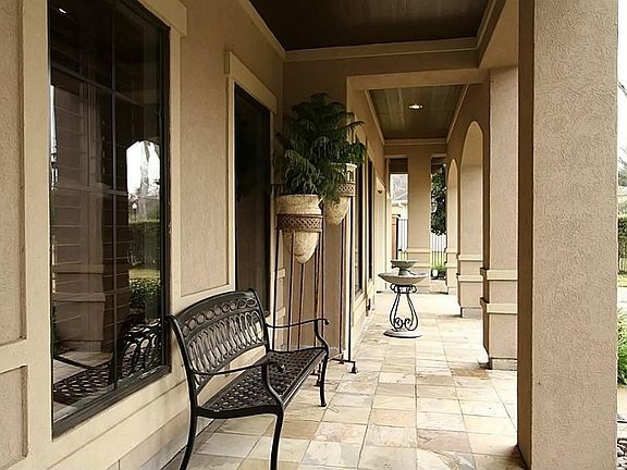 WITHIN THE ALL STUCCO EXTERIOR, THIS FRONT LOGGIA WITH COLUMNS & SLATE WELCOMES YOU AND YOUR GUESTS 