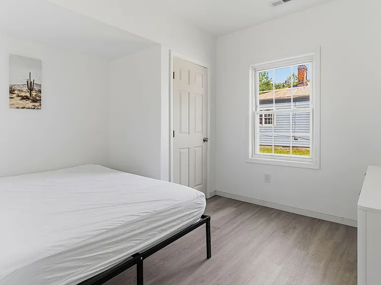 Private bedroom with a large window, neutral walls, and durable flooringideal for a bed, dresser, and personal storage.