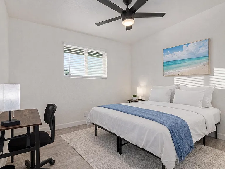 Queen Size room facing front of home. Desk, lamp, fan, closet. Bedding and rug virtually staged.