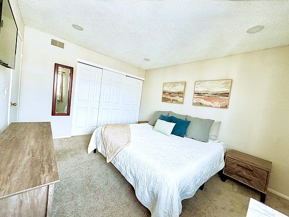 Bedroom angle from the window with smart TV above the credenza and full length mirror that has hidden hinges for jewelry storage