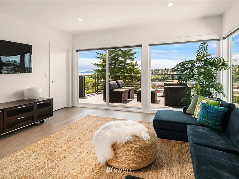 Top-floor room with floor-to-ceiling windows and sliding doors offering direct access to a spacious, partially covered deck.