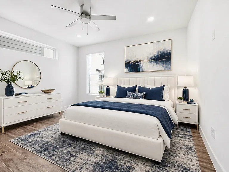 Spacious primary bedroom featuring wood- look tile finish flooring, recessed lighting, a contemporary ceiling fan, a horizontal clerestory window, and a vertical window with blinds.