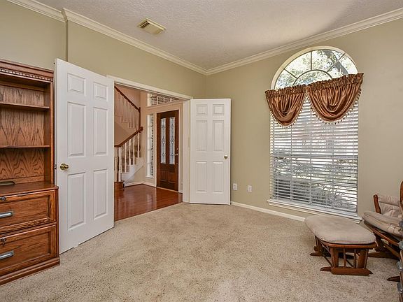 Private study with crown molding, plush carpet, neutral colors and double doors