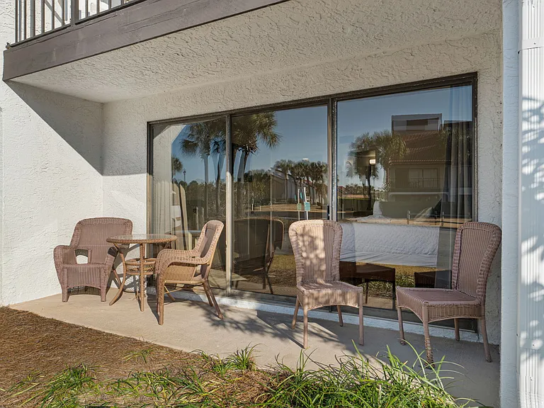 Just outside the King Guest Bedroom is a patio with multiple wicker chairs and a table.