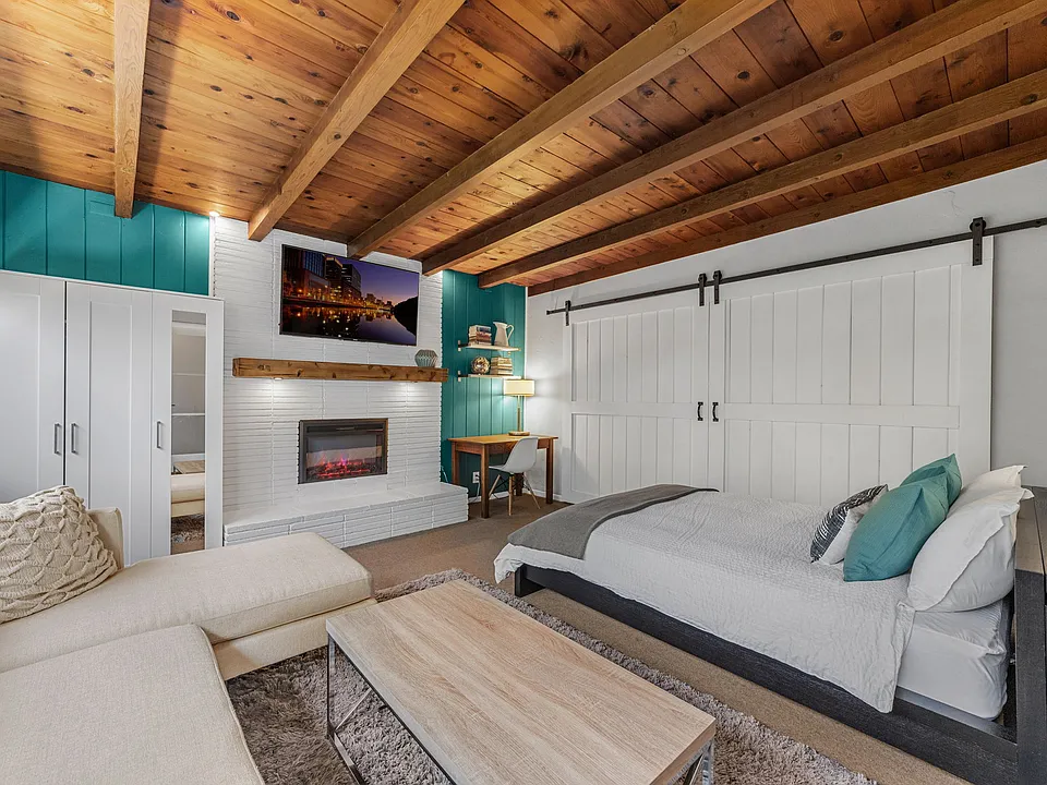 Studio guesthouse w/open beam ceilings, fireplace, sofa, queen bed, wardrobe, 65" SmartTV and home office.