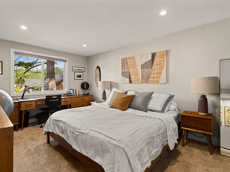 fiurnished primary bedroom with dresser, king bed, 2 nightstands and office furniture