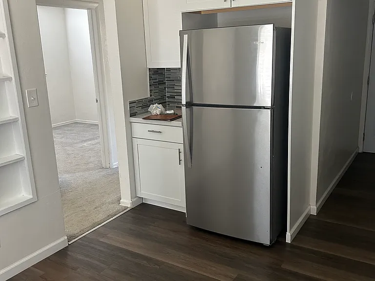 Standing at the front window, the stainless steel refrigerator To the right is the laundry room and to the left is the doorway to the hall.