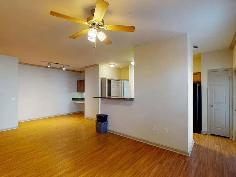 Apartment kitchen, dining and living room with wood-style flooring.