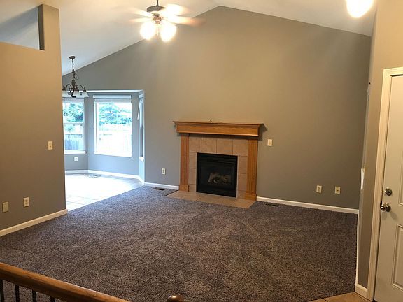 Living room with fireplace, ceiling fan, and vaulted ceiling