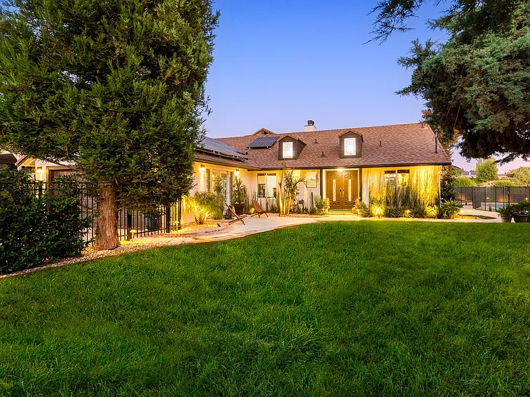 Private landscaped backyard with lush lawn and evening lighting-ideal for entertaining and family living