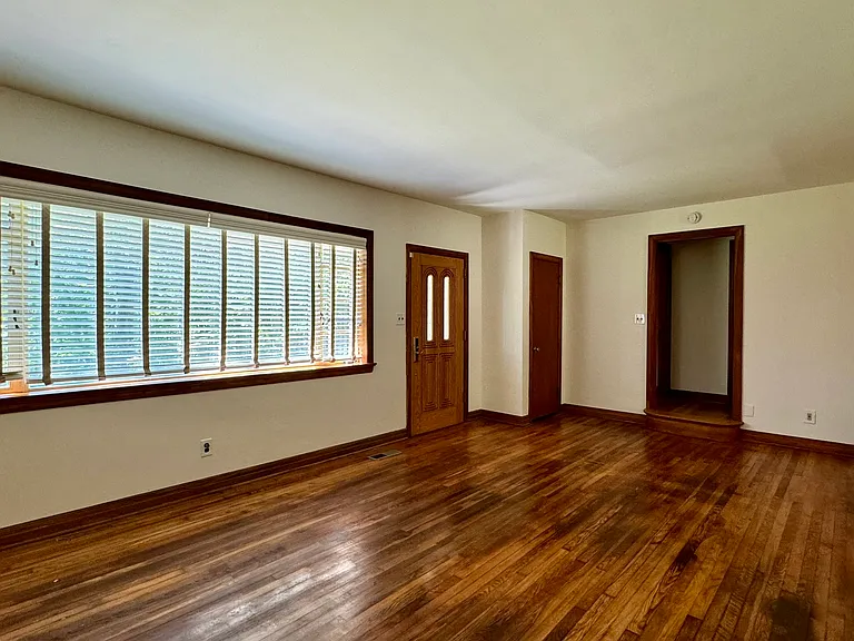 Living room with hardwood flooring; looking into hallway for Bedrooms 1&2 plus Bathroom 1; entry into Dining Room to the right.