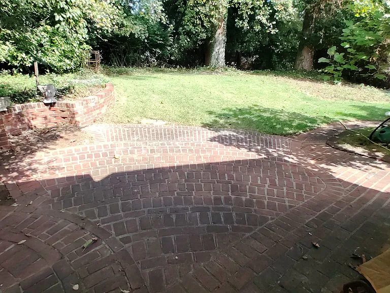 Shaded Brick Patio leading to a flat, fenced backyard.