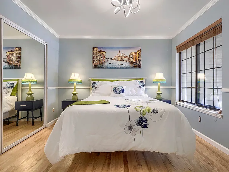 Primary Bedroom _A serene retreat featuring rich red oak hardwood floors, abundant natural light, and spacious mirrored closet that combine style and functionality.