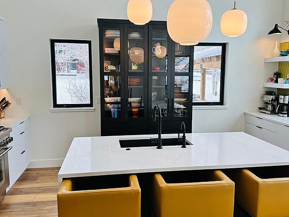 Kitchen with bar seating, custom hutch, hand blown glass hanging pendents.