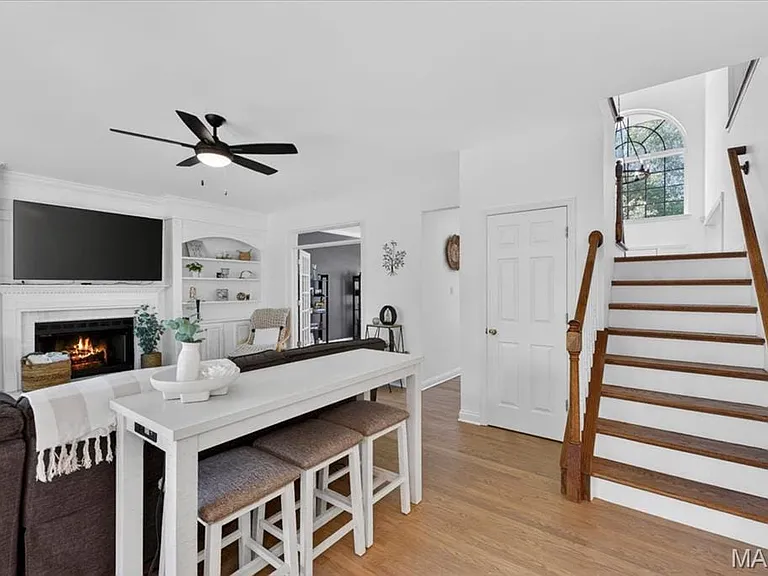 Living area featuring a fireplace with a mantel, built-in shelving, and a ceiling fan
