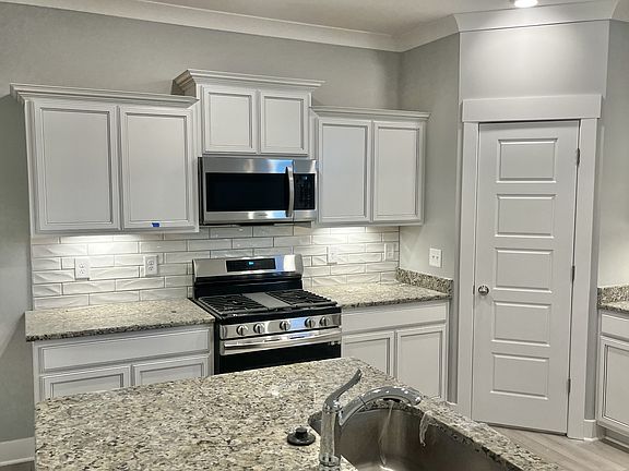 Close up showing textured backsplash and undercabinet lighting. Large corner pantry and large singl