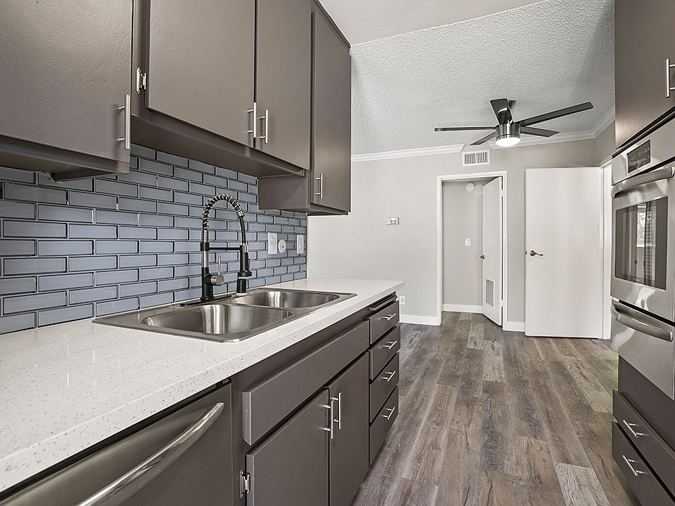 Blue tiled kitchen with stainless steel oven, microwave, and fixtures.
