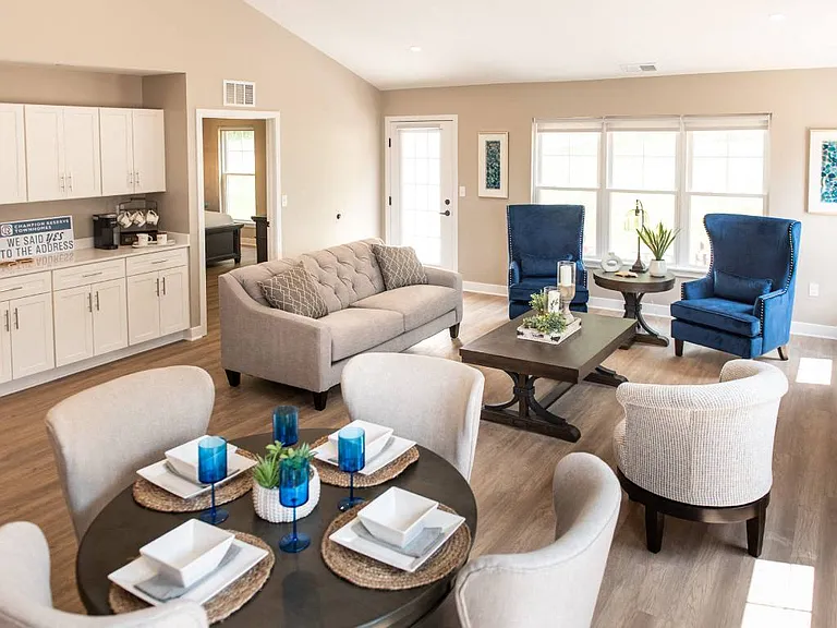 Interior of Champion Reserve Townhome Great Room showing living area, dining area, coffee bar, and doors to private patio and primary bedroom.