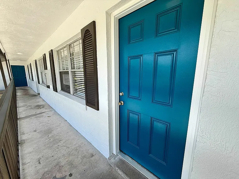Inviting apartment entrance with a vibrant blue door and charming windows, offering warmth and style.