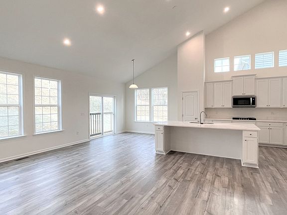 Open main floor with wall of windows recessed lights wood floors in a DRB Homes Aspen II plan at T