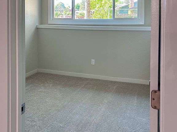 Comfortable bedroom with large window, ceiling fan, and plush carpet.