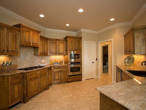 Spacious Kitchen features exotic granite counters, tumbled marble backsplash, under cabinet lighting, tile floors set in Versailles pattern and extensive crown moulding.