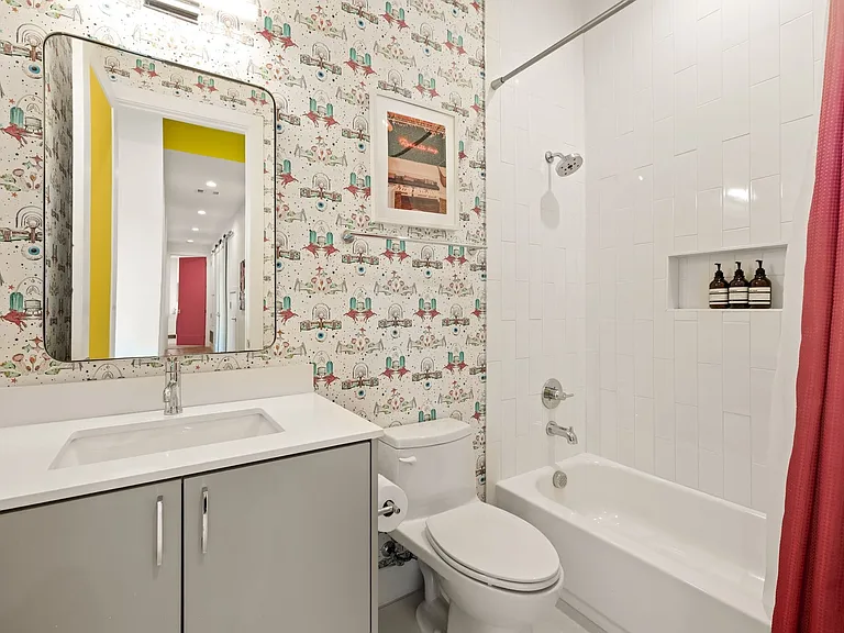 Bathroom featuring a single vanity with an integrated sink, a rectangular mirror, and a white tiled shower/tub combination