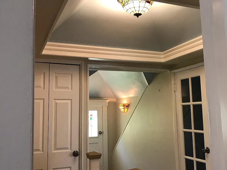 at top of stairs showing doors to two storage rooms (left and right)
and hallway leading to balcony entrance on left. Bedroom and living room entrances
are on right but not shown. Note fancy vaulted ceiling with leaded glass chandelier