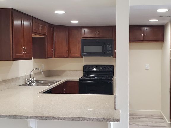 View of kitchen layout. All new lighting. New hardwood cabinets. New quartz countertops. Appliances are all electric. Includes dishwasher, stove/oven and microwave. Area accomodates standard size refrigerators (not included).