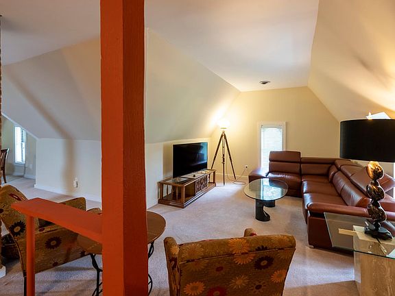 Living room with wrap around chocolate leather couch, seating area and SMART TV/Direct.