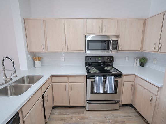 Kitchen w/ stainless steel appliances, quartz counters, and tile backsplash