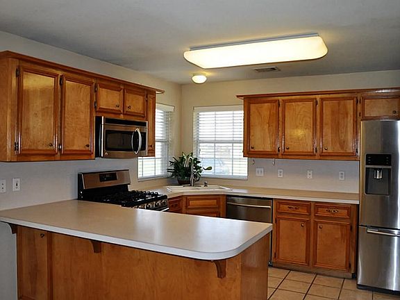 Gourmet Kitchen w/Wood Cabinetry, Stainless Steel Appliances, 5 Burner Gas Stove/Oven, Fridge, Double Door Pantry, Breakfast Bar, & Lots of Cabinets and Counter Space.
