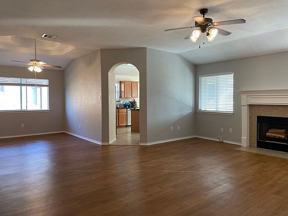 Living room with woodburning fireplace, dining room, and vinyl plank flooring.