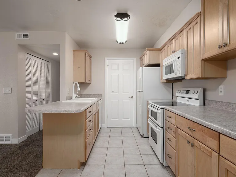 Kitchen view #2. The laundry closet is behind the door. There's a dishwasher to the right of the sink.